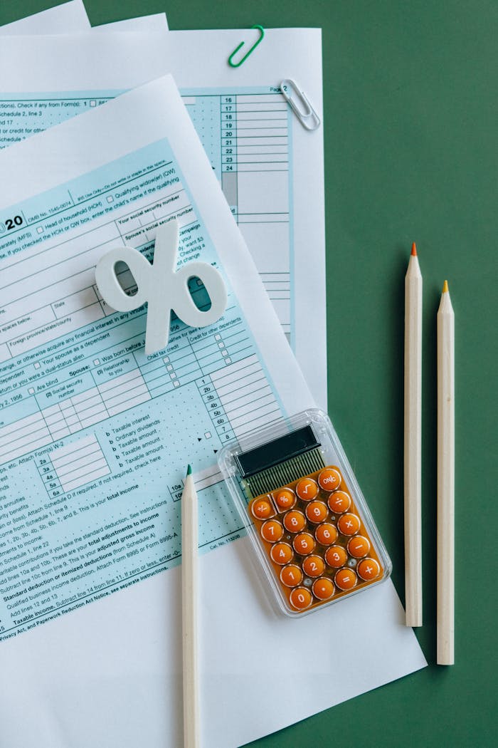 services-04 Flat lay of tax documents, calculator, and pencils on green surface.