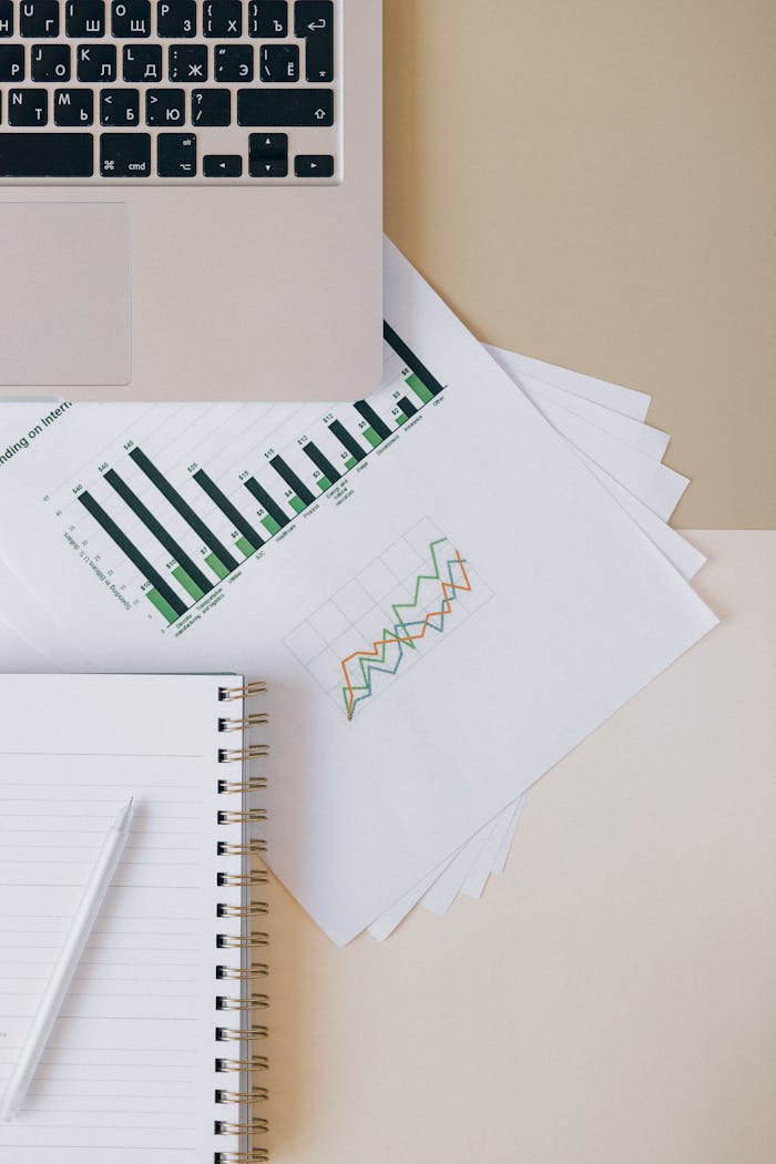 about-us Flat lay of a workspace featuring a laptop, graphs, and a notebook for financial analysis.